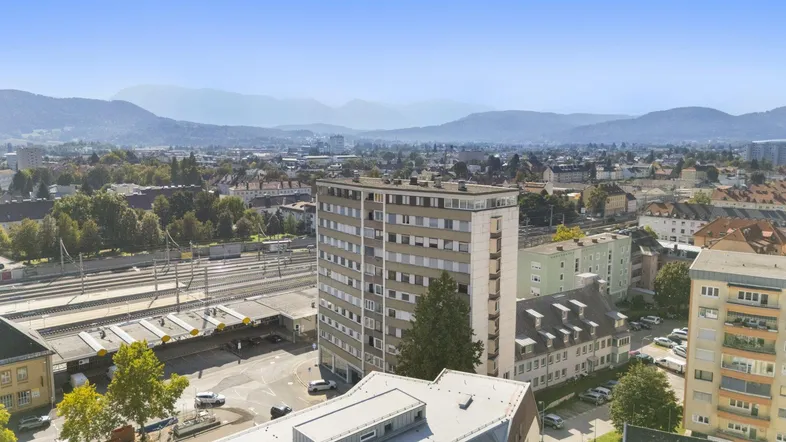 Luftaufnahme eines Wohngebäudes in der Stadt mit Blick auf die umliegende Landschaft und Berge.