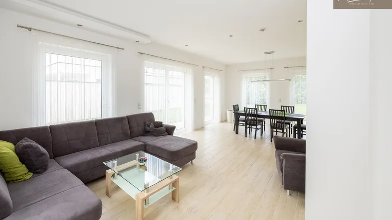 Helles und offenes Wohn-Esszimmer mit großem Sofa, Esstisch und Zugang zum Garten.
