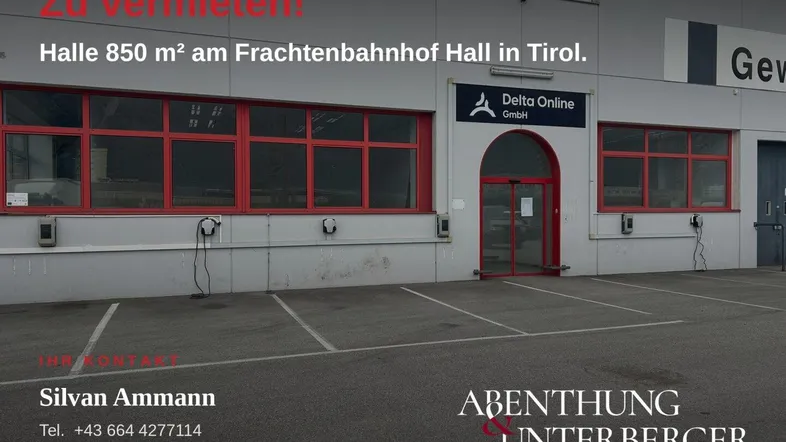 Außenansicht eines Gewerbegebäudes mit roten Fensterrahmen, Parkplätzen und Ladestationen für Elektrofahrzeuge.
