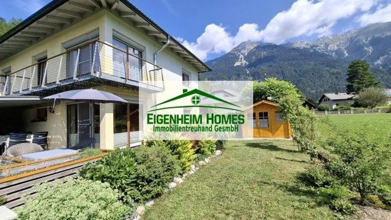 Modernes Haus mit Terrasse, Garten und beeindruckendem Bergblick in alpiner Umgebung.