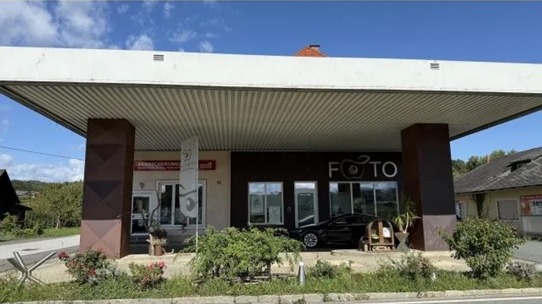 Gebäude mit überdachtem Eingangsbereich und Geschäftsfassaden unter blauem Himmel.