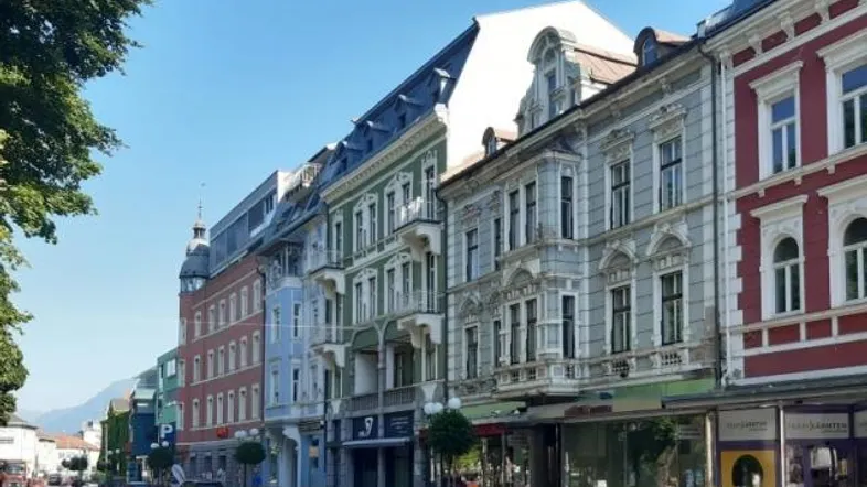 Historische Gebäudezeile mit Geschäften und Blick auf die Berge in einer Stadt.