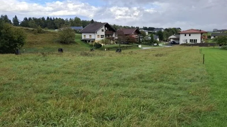 Weitläufiges Grundstück mit Blick auf die umliegende Wohnbebauung und grüne Hügel.