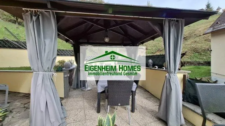 Überdachte Terrasse mit Gartenmöbeln und Vorhängen, ideal für entspannte Stunden im Freien.