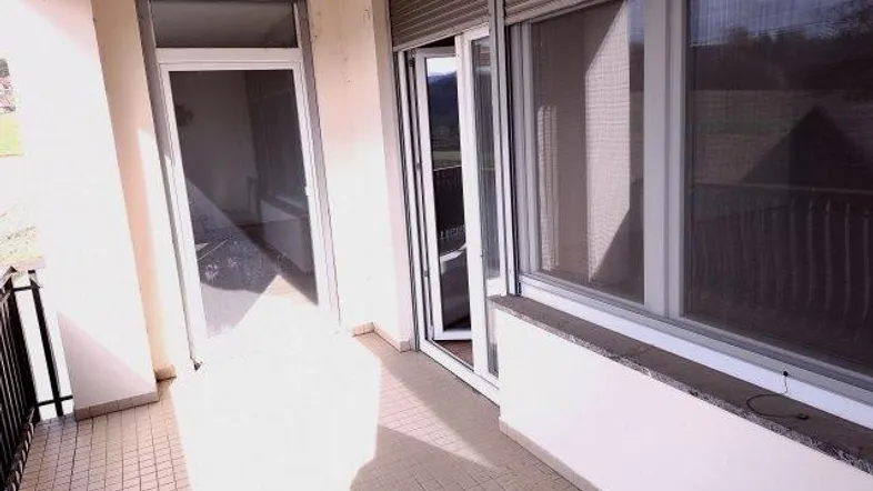Heller Balkon mit Fliesenboden, Rollläden und Zugang zu den Innenräumen, sonnendurchflutet.