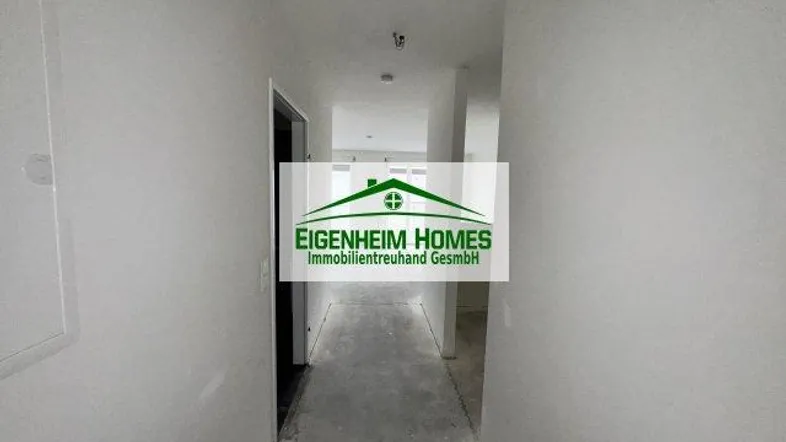 Unfertiger Flur in einem Neubau mit Rohbauzustand und Betonboden, bereit für den Ausbau.