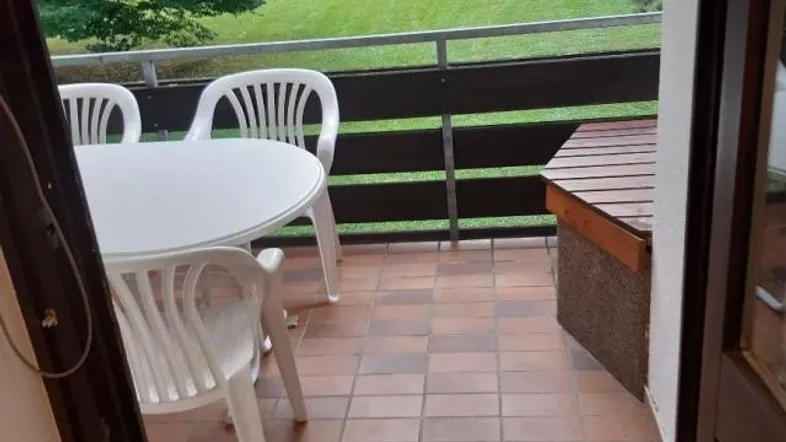 Möblierter Balkon mit Fliesenboden und Blick ins Grüne, ideal zum Entspannen im Freien.