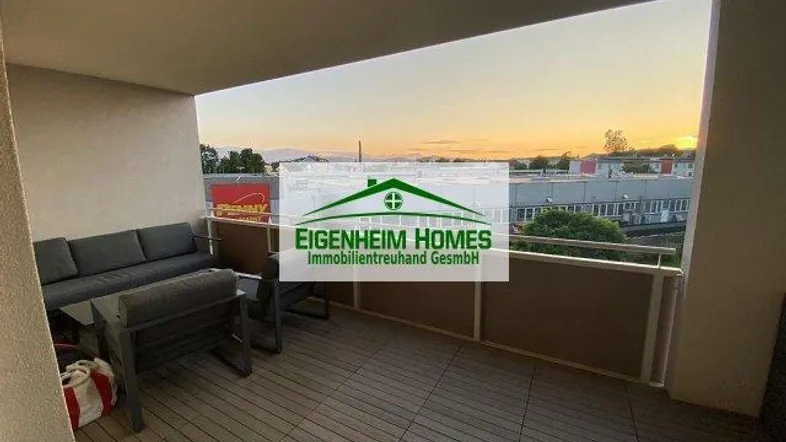 Geräumiger Balkon mit bequemen Outdoor-Möbeln und weitem Blick auf die Umgebung bei Sonnenuntergang.
