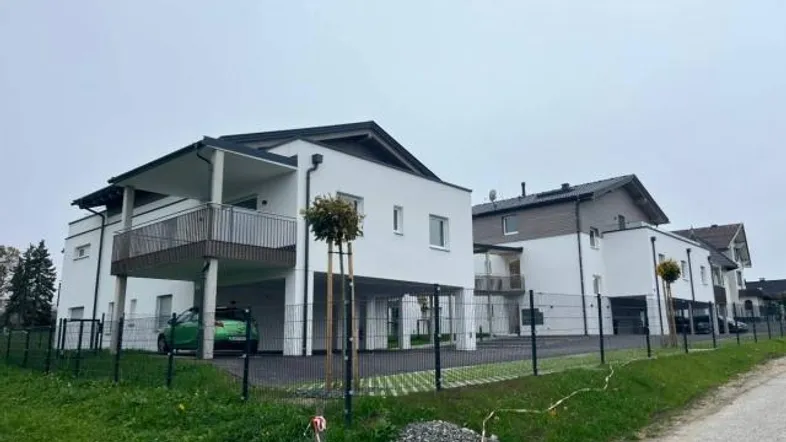 Moderne weiße Mehrfamilienhäuser mit Balkonen und Carports in einer Wohnsiedlung.