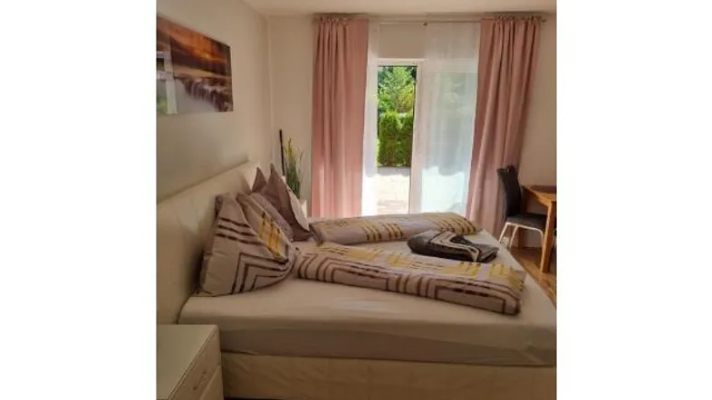 Helles Schlafzimmer mit Doppelbett, Holzboden und direktem Zugang zur Terrasse.