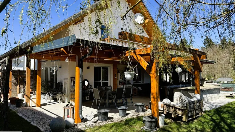 Geräumige überdachte Terrasse mit Essbereich und Lounge-Möbeln, umgeben von einem gepflegten Garten.