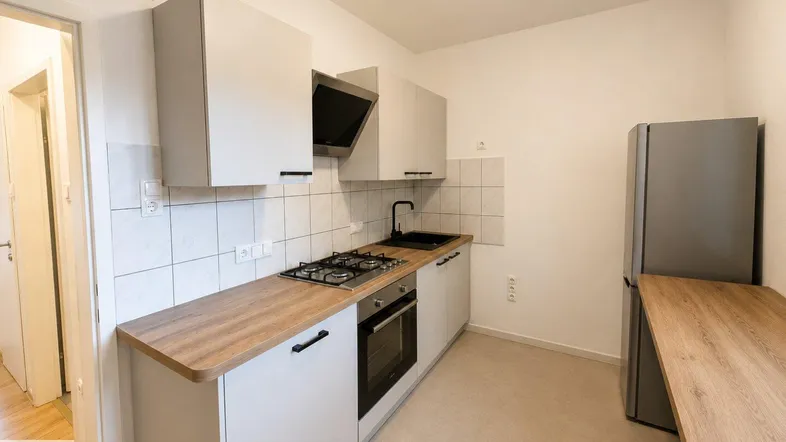Moderne Küche mit hellgrauen Schränken, Holzarbeitsplatten, Gasherd und integriertem Backofen.