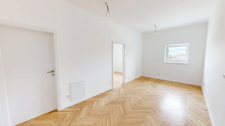 Heller Raum mit Fischgrätparkettboden und weißen Wänden, bereit für die individuelle Gestaltung.
