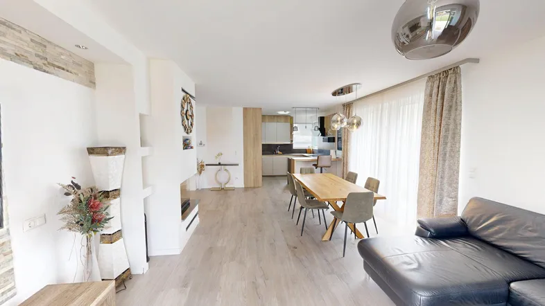 Helles, offenes Wohn- und Esszimmer mit moderner Küche und Holzboden in einem modernen Haus.