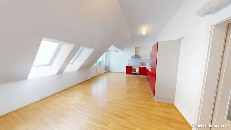 Heller offener Wohnbereich mit integrierter roter Küche, Dachschrägen und Holzboden.