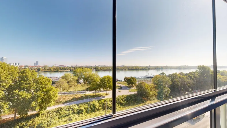Blick aus einem modernen Wohnraum auf den Fluss und die Stadt mit weitem Horizont.