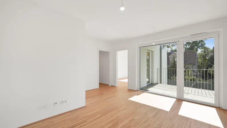 Helles Wohnzimmer mit Parkettboden und Zugang zu einem sonnigen Balkon.