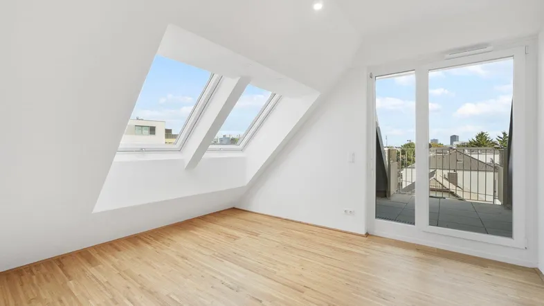 Helles Dachgeschosszimmer mit Holzboden, zwei Dachfenstern und Zugang zu einer Terrasse.