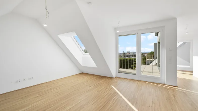 Heller Raum mit Holzboden, Dachschrägen, Dachfenster und Zugang zu einem Balkon mit Stadtblick.