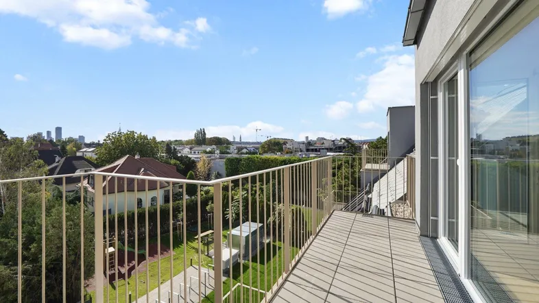 Geräumiger Balkon mit Fliesenboden und weitem Blick über grüne Umgebung und die Stadt.