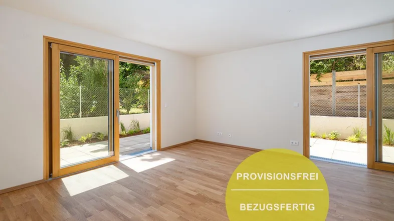 Helles Zimmer mit Holzboden und großen Schiebetüren, die zu einer Terrasse führen.