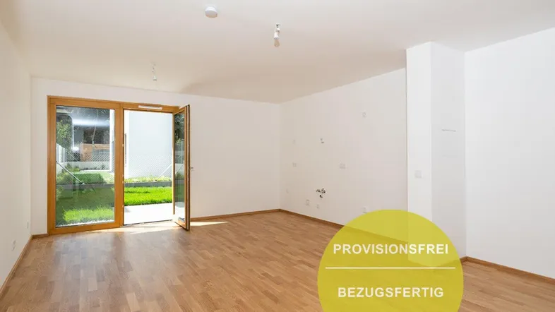 Helles, leeres Wohnzimmer mit Holzboden und direktem Zugang zum grünen Gartenbereich.