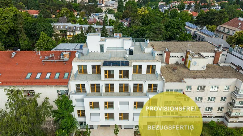 Moderne Wohnanlage mit Flachdach und Solarpaneelen in städtischer Umgebung, umgeben von Grünflächen.