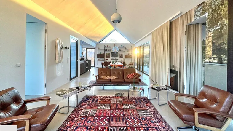 Geräumiges Wohnzimmer mit hohen Decken, großen Fenstern und gemütlichen Ledersofas.