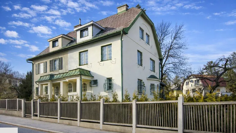 Elegantes Wohnhaus mit klassischer Architektur, weißer Fassade und gepflegtem Vorgartenbereich.