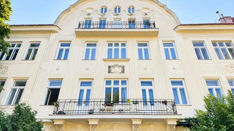 Elegante Fassade eines Altbaus mit dekorativen Elementen und Balkonen unter blauem Himmel.