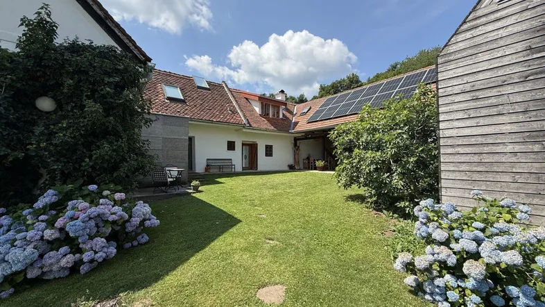 Großer grüner Gartenbereich mit blühenden Hortensien und Blick auf das Wohnhaus mit Solaranlage.