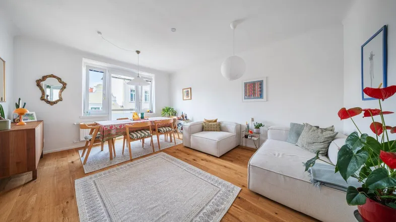 Helles Wohn- und Esszimmer mit Holzboden, modernen Möbeln und einem großen Esstisch.