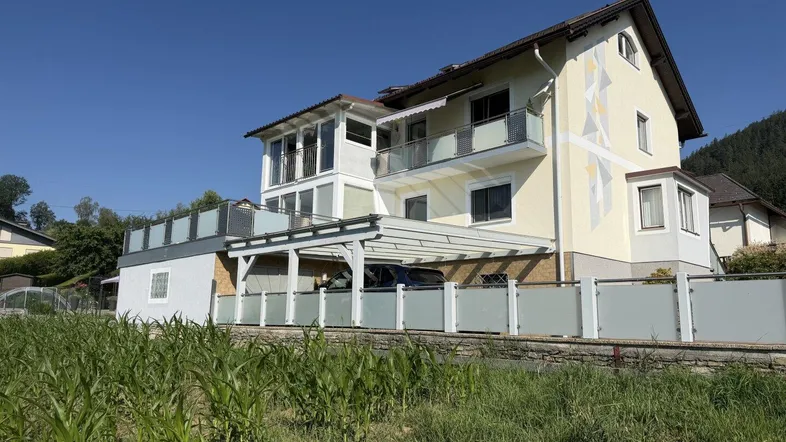 Modernes Haus mit mehreren Balkonen, Carport und Bergblick in sonniger Lage.