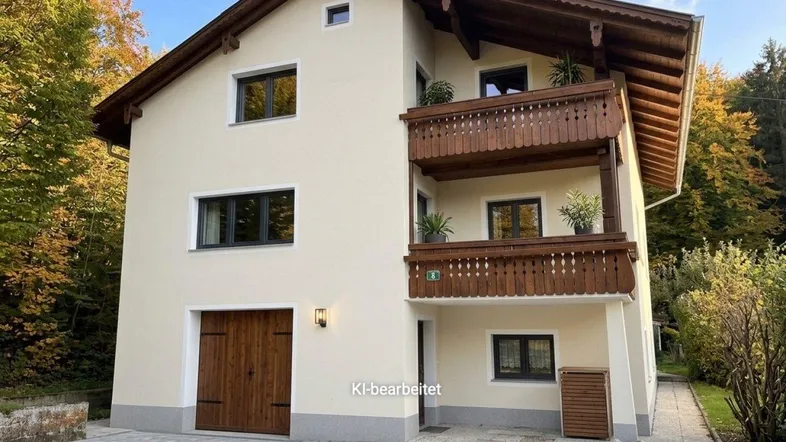 Charmantes Einfamilienhaus mit traditionellem Holzbalkon und gepflasterter Auffahrt, umgeben von Herbstbäumen.