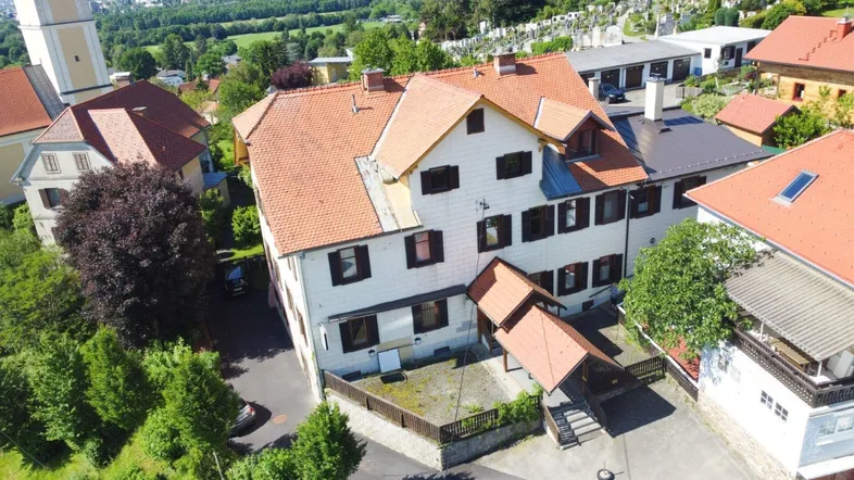 Luftaufnahme eines Gebäudes mit rotem Ziegeldach und umliegender grüner Landschaft.