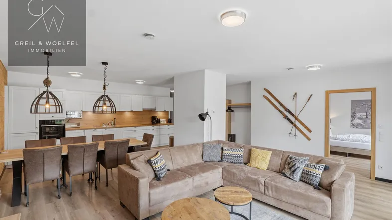 Geräumiger offener Wohn-Essbereich mit moderner Küche, gemütlichem Sofa und Holzakzenten.