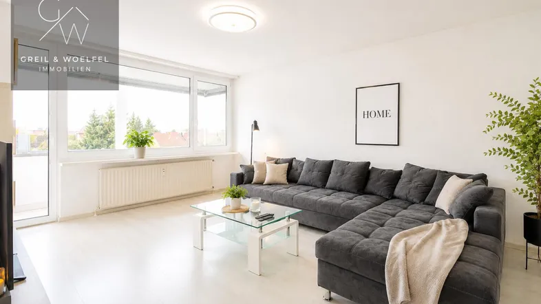 Helles Wohnzimmer mit großem Ecksofa, Glascouchtisch und Zugang zum Balkon.
