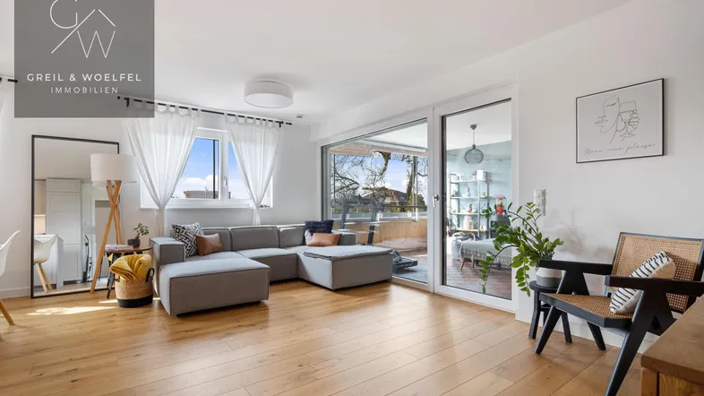 Helles Wohnzimmer mit Holzboden, großem Sofa und direktem Zugang zu einem Außenbereich.