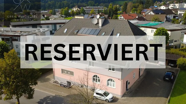 Luftaufnahme eines gepflegten Wohnhauses mit Satteldach, Solaranlage und Parkplätzen in grüner Umgebung.