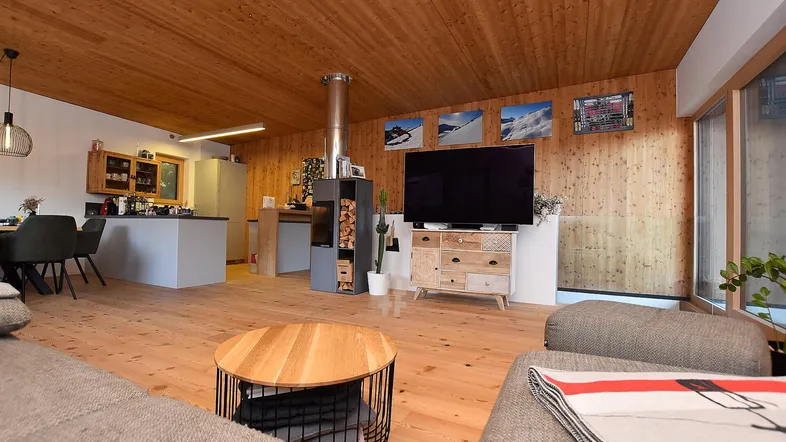Geräumiger offener Wohn- und Essbereich mit Holzboden, Kaminofen und integrierter Küche.