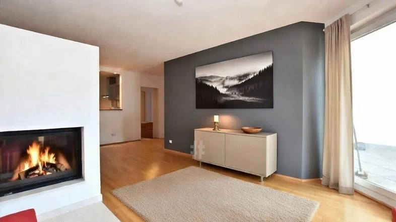 Helles Wohnzimmer mit Kamin, Holzboden und Zugang zu einem Balkon.