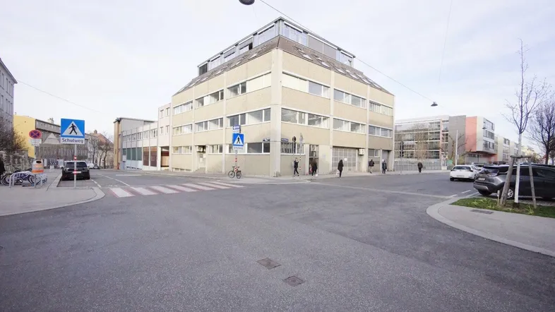 Mehrstöckiges Geschäftsgebäude an einer Straßenecke mit umliegenden Straßen, Fußgängerüberwegen und parkenden Autos.