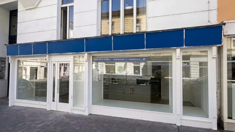 Vorderansicht eines Geschäftsgebäudes mit großen Schaufenstern und einer blauen Markise.