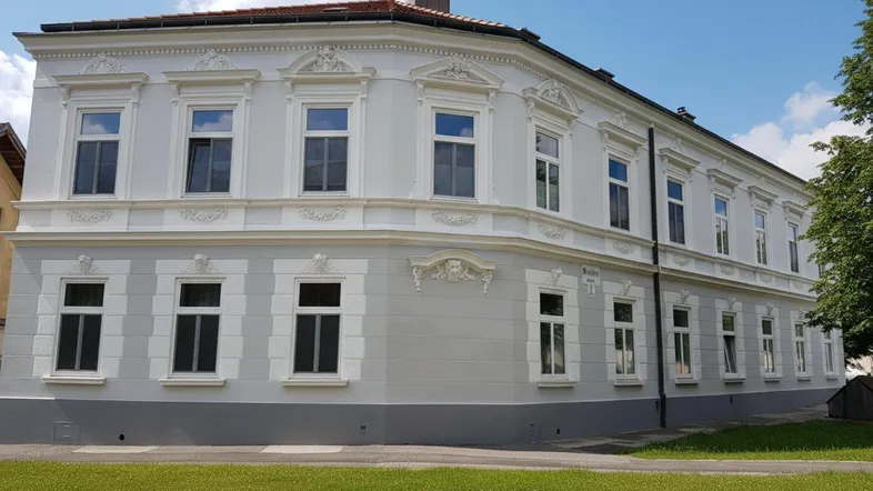 Elegantes historisches Gebäude mit frisch renovierter Fassade und dekorativen Stuckelementen an einem sonnigen Tag.