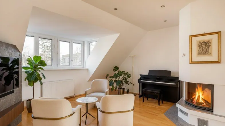 Helles Wohnzimmer mit Kamin, Klavier und Dachschrägen, ausgestattet mit gemütlichen Sesseln.