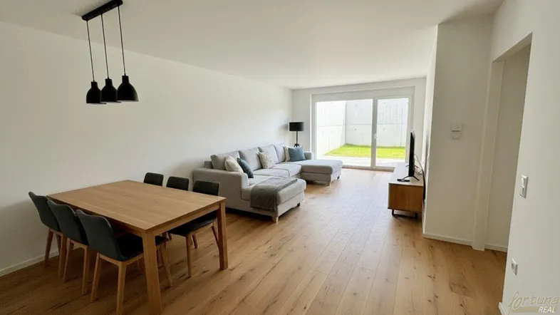 Helles Wohn- und Esszimmer mit Holzboden, bequemer Couch und direktem Zugang zum Garten.