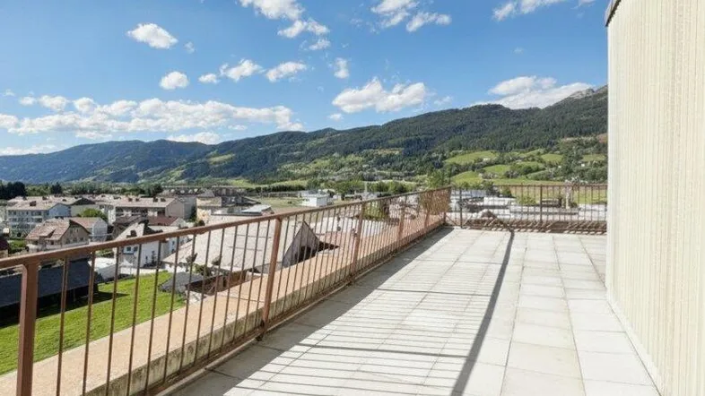 Große geflieste Dachterrasse mit Metallgeländer und weitem Blick auf die umliegende Berglandschaft.