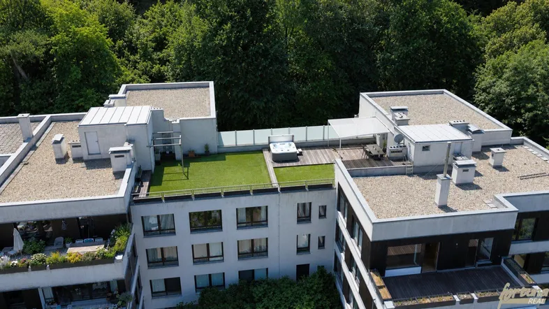 Luftaufnahme eines modernen Wohnkomplexes mit begrünten Dachterrassen, Whirlpool und Sitzbereichen.