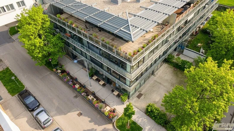 Luftaufnahme eines modernen Gebäudes mit mehreren Terrassen und begrünten Außenbereichen.