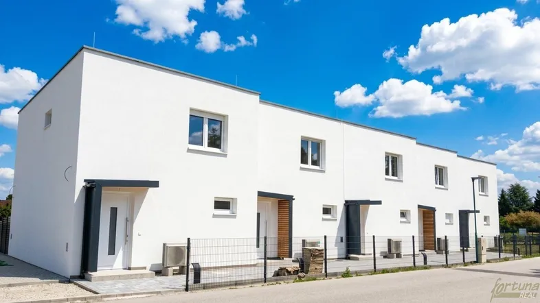 Moderne Reihenhäuser mit weißer Fassade und klaren Linien unter blauem Himmel.